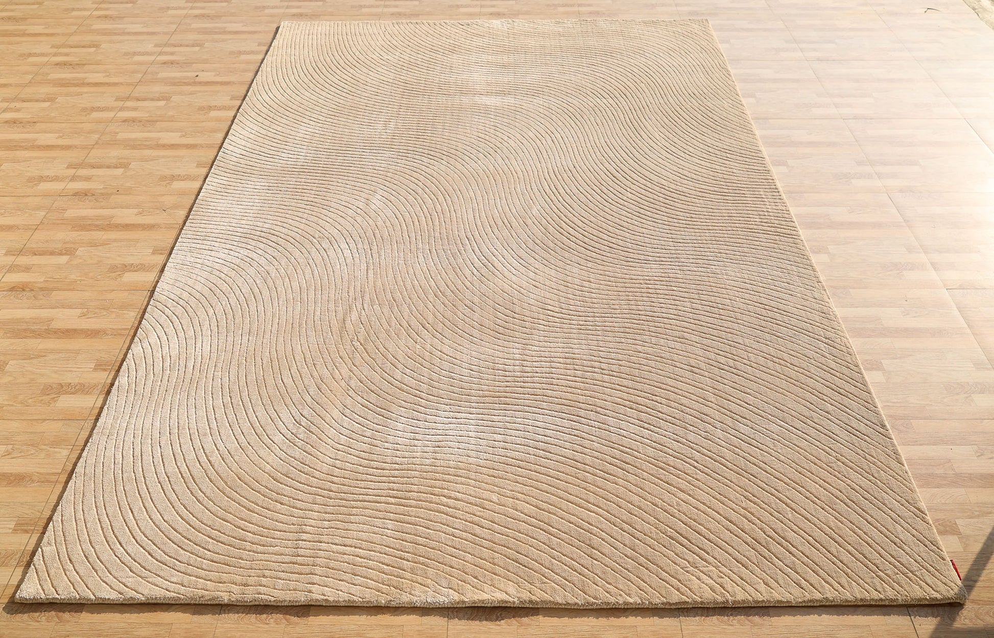 The RAMSHA HOME Handmade beige Wave Modern Abstract High-Low Area Rug (250x350 cm, LKH-049) features embossed wave-like textured lines, adding a subtle sense of movement to any light wood floor.