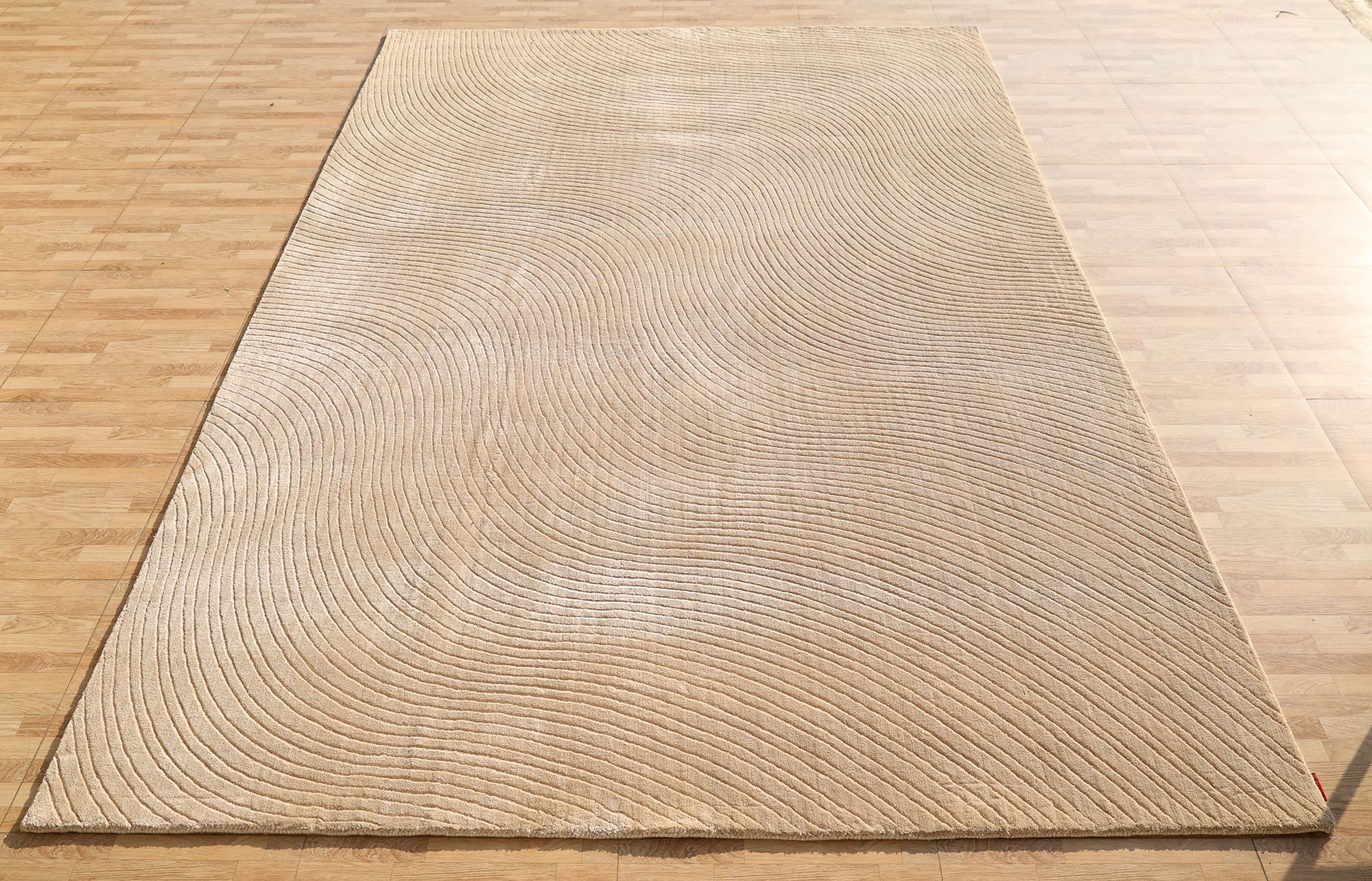 The RAMSHA HOME Handmade beige Wave Modern Abstract High-Low Area Rug (250x350 cm, LKH-049) features embossed wave-like textured lines, adding a subtle sense of movement to any light wood floor.