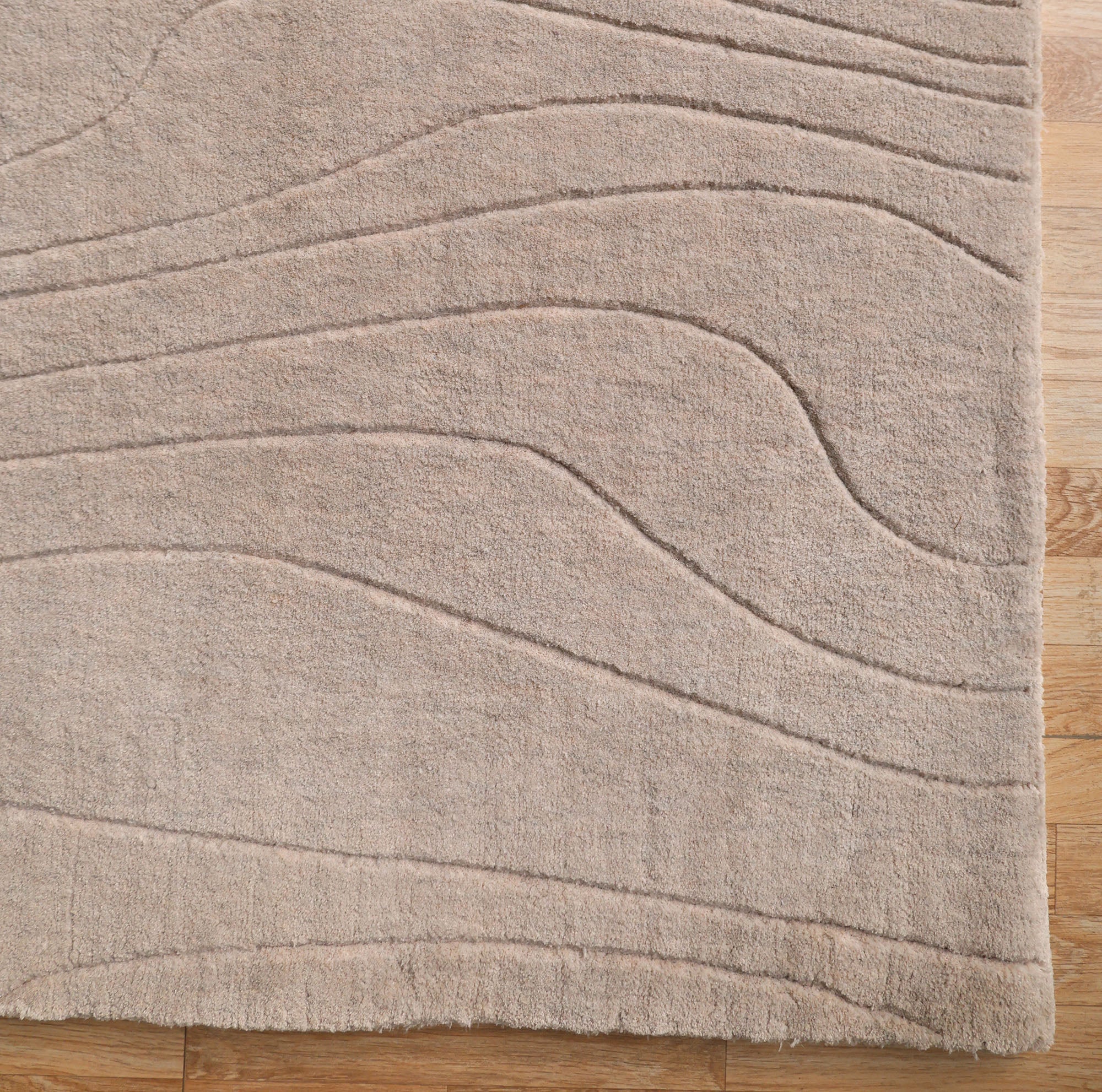 The RAMSHA HOME Light Grey Color Handmade 250x350 cm Area Rug (LKH-043) features subtle, wavy, raised line patterns and is displayed on a light wooden floor.