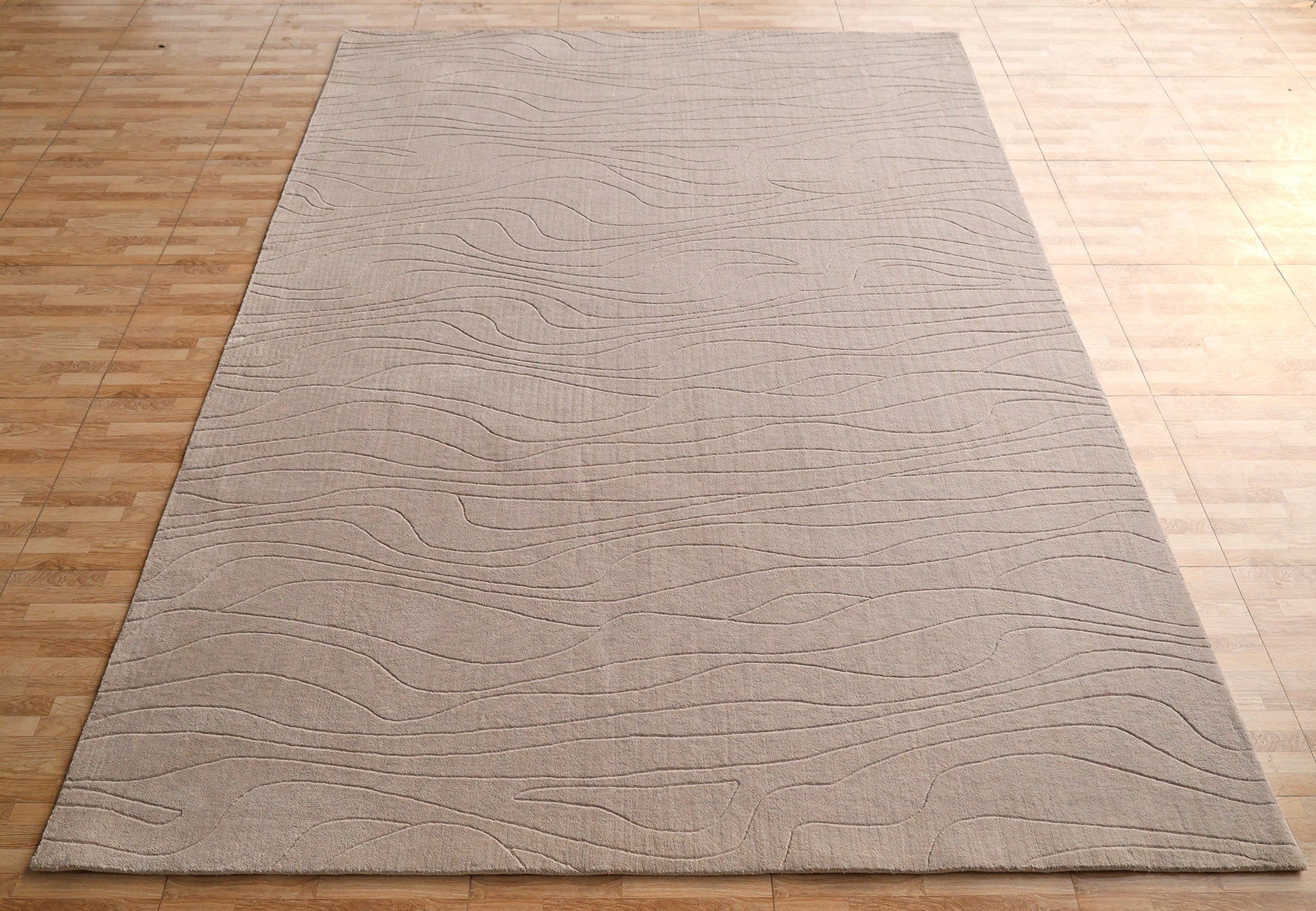 The RAMSHA HOME Light Grey Color Handmade 250x350 cm Area Rug (LKH-043) features subtle, modern wavy line patterns, offering a minimalist look that enhances any space.