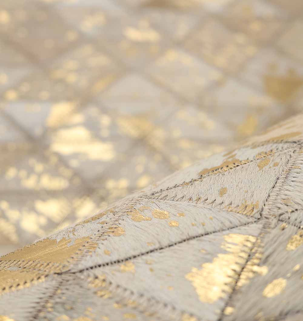 A close-up of the Amazing Grey & Tan Color Playroom Leather Rug - LR 006 showcases geometric quilted patterns, shimmering gold accents on a cream and beige background, and visible stitched outlines.