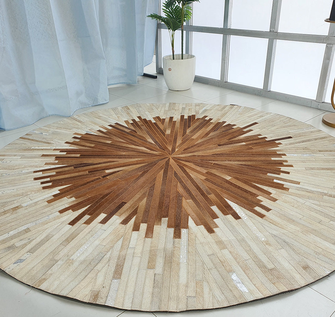 The Multi Color Round Leather Rug - LR 016 in brown and beige sits on a white tile floor near a potted plant, sheer blue curtains, and large windows, brightening the space with natural light.
