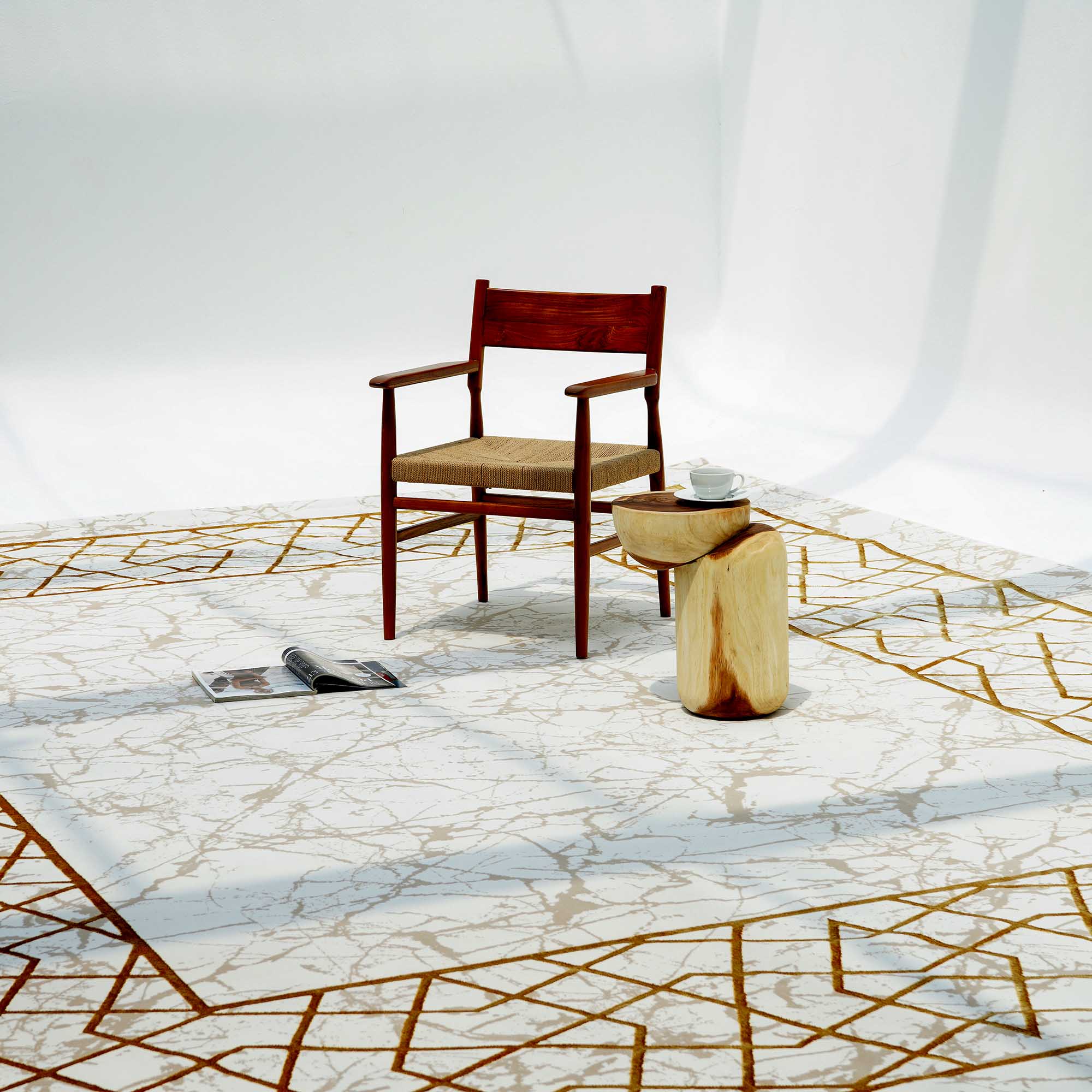 A wooden chair with a woven seat sits on the Cream, Shrink Cream Colored Geometry Pattern Turkey Rug MZ67C by RAMSHA HOME, atop a marble floor next to a natural wood side table with a white teacup and saucer; an open magazine lies nearby.