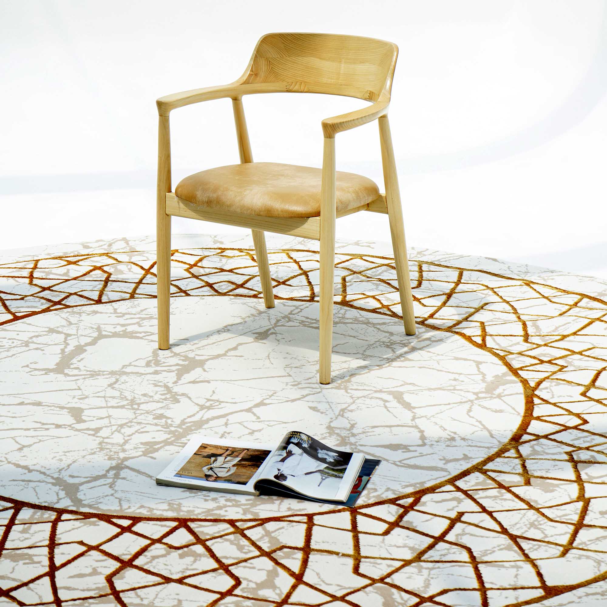 A wooden chair with a curved backrest sits on the RAMSHA HOME Cream, Shrink Cream Colored Geometry Pattern Turkey Rug MZ67C. An open magazine lies on the rug, creating an inviting atmosphere.