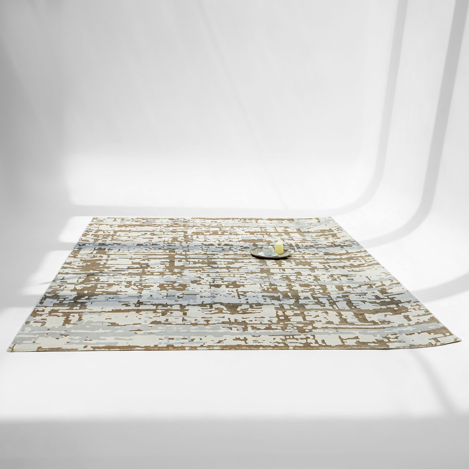 The RAMSHA HOME Stunning Abstract Pattern Machine Made Rug - MZ40K in brown and beige lies on a white surface, topped with a tray holding a cup and lemon, as soft shadows cross the scene.