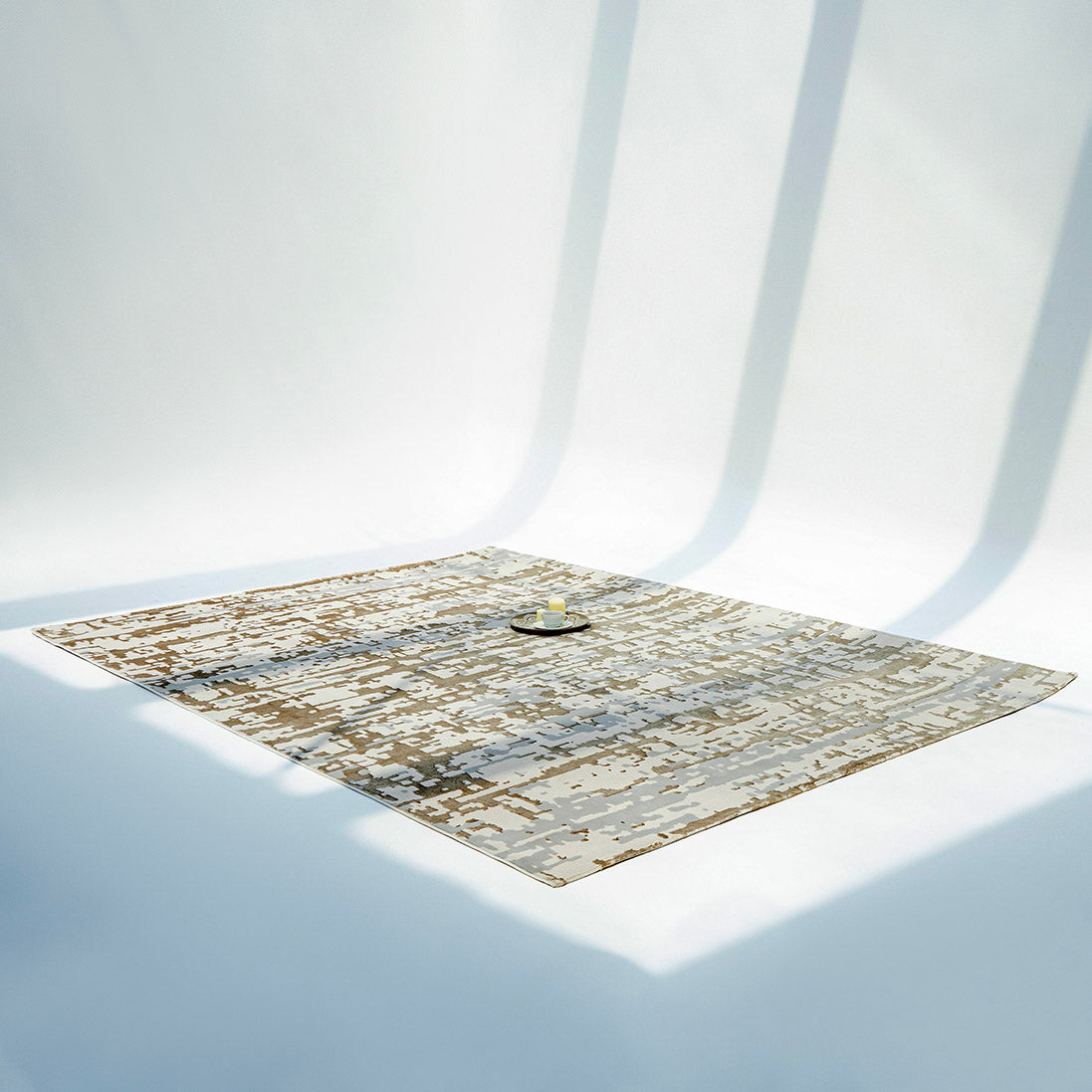 The RAMSHA HOME Stunning Abstract Pattern Machine Made Rug - MZ40K, featuring neutral tones, is spread over a white floor under bright natural light, with a small tray holding a teapot and cups placed at its center.