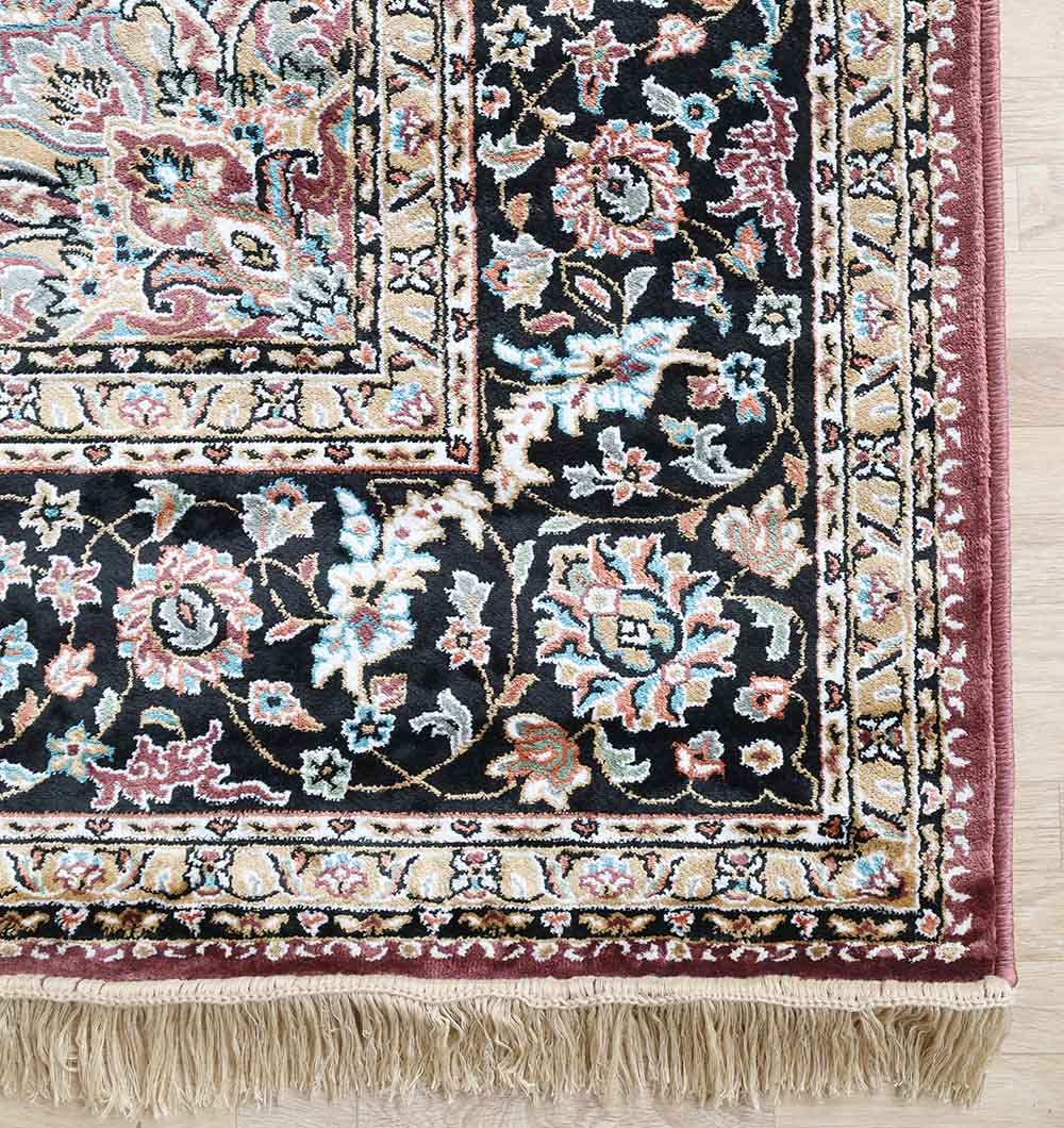 Corner of RAMSHA HOME's Persian Floral Medallion Burgundy Rug with Black Border (MMB 04, 150x210 cm), a machine-made polyester piece featuring ornate black, cream, blue, and burgundy patterns with fringed edges on a light wooden floor.