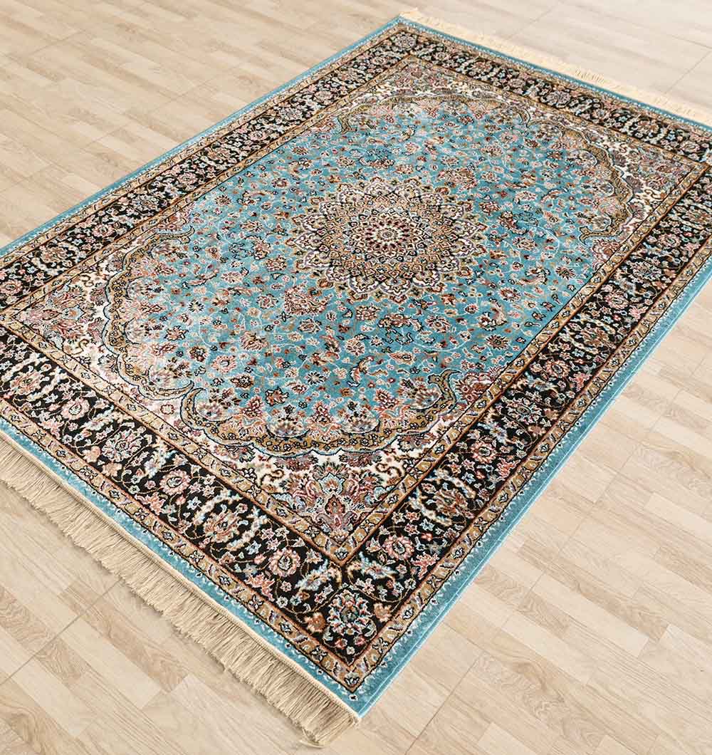 The RAMSHA HOME Persian Floral Medallion Teal Blue Rug with Black Border – MMB 05 (150x210 cm) features a detailed central medallion and ornate borders in blue, brown, cream, and black, shown on a light wood floor.