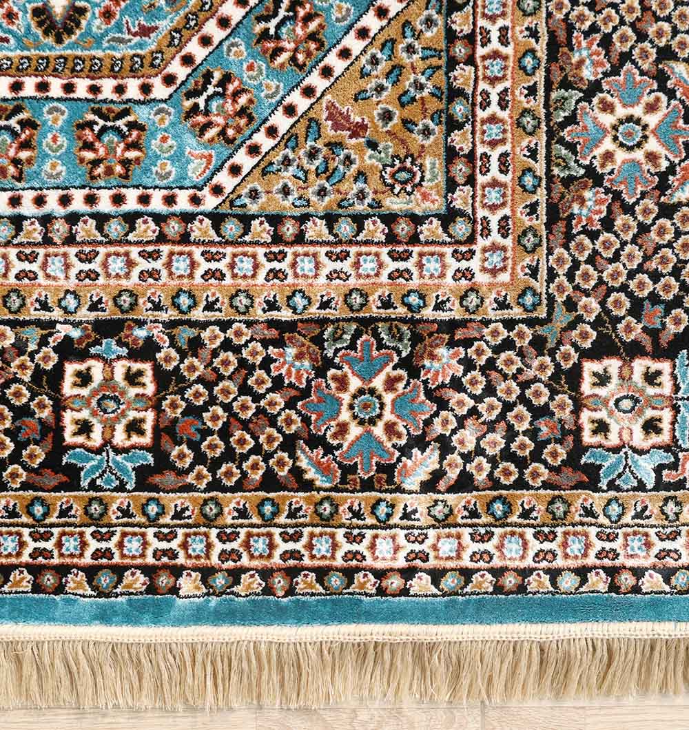 The RAMSHA HOME Persian Medallion Teal Blue Rug with Black Border – MMB 06 (175X275 cm) showcases intricate geometric and floral patterns in blue, gold, black, and white with fringe along the edge, displayed on a light wooden floor.