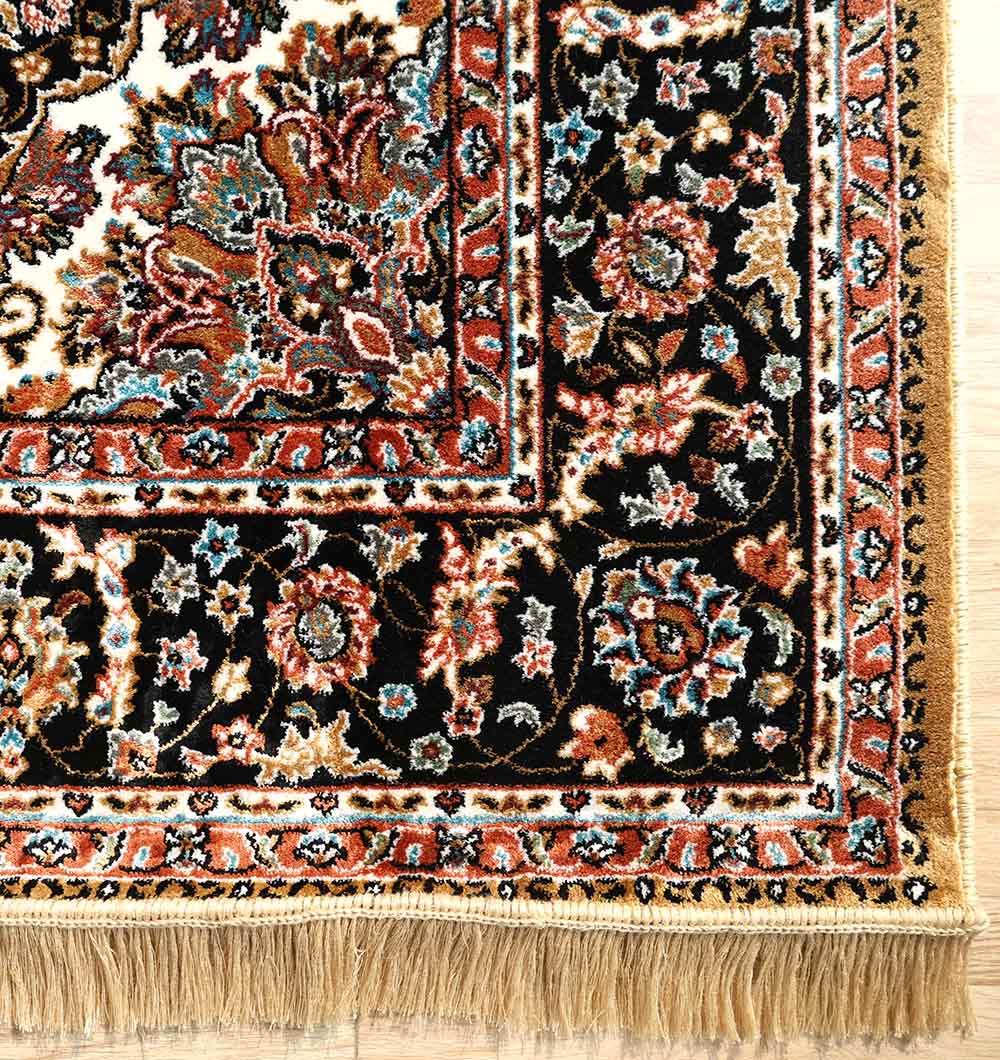 The RAMSHA HOME Persian Floral Medallion Rust & Black Border Rug – MMB 09 (175X275 cm) features intricate floral patterns in red, blue, cream, and gold on a black field with a floral border and beige fringe, shown here on a wooden floor.