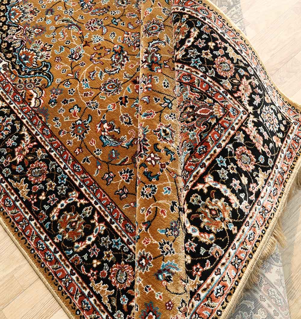 The RAMSHA HOME Persian Floral Medallion Rust & Black Border Rug – MMB 09 (175×275 cm) is partially folded on a wooden floor, showing its elegant patterned design with floral motifs and distinct rust and black borders.