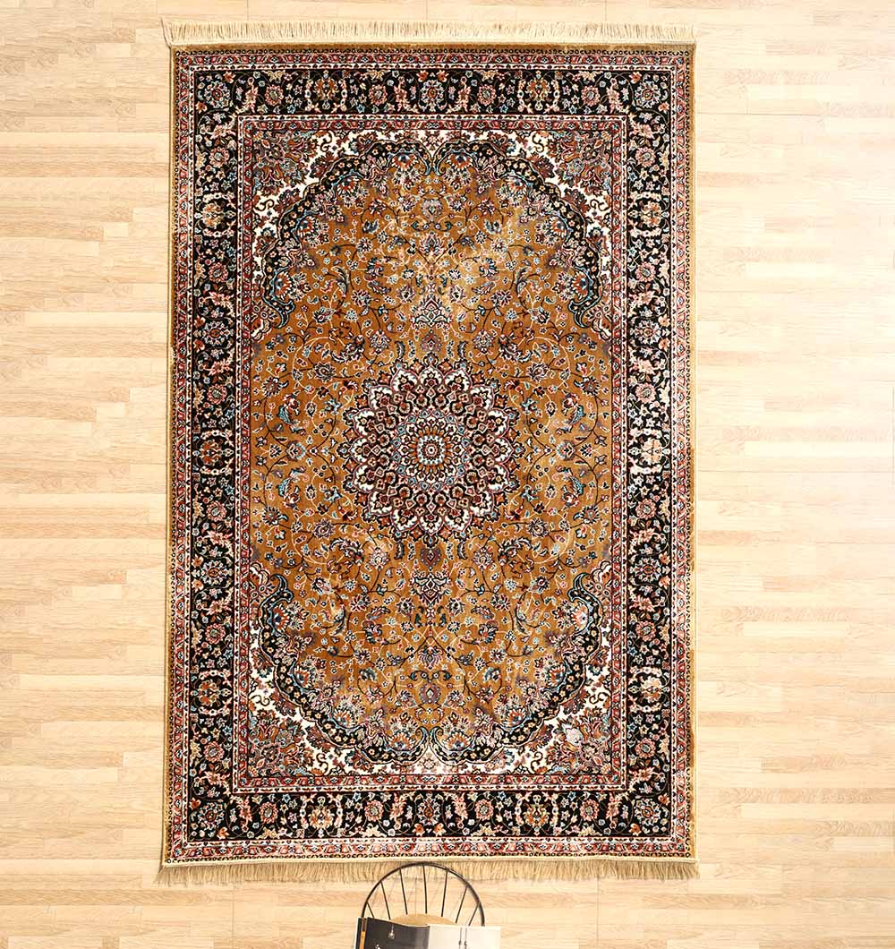 The RAMSHA HOME Persian Floral Medallion Rust & Black Border Rug – MMB 09 (175x275 cm) lies on a light wooden floor, featuring intricate patterns in rust, black, and white with a black chair partially visible at the bottom.