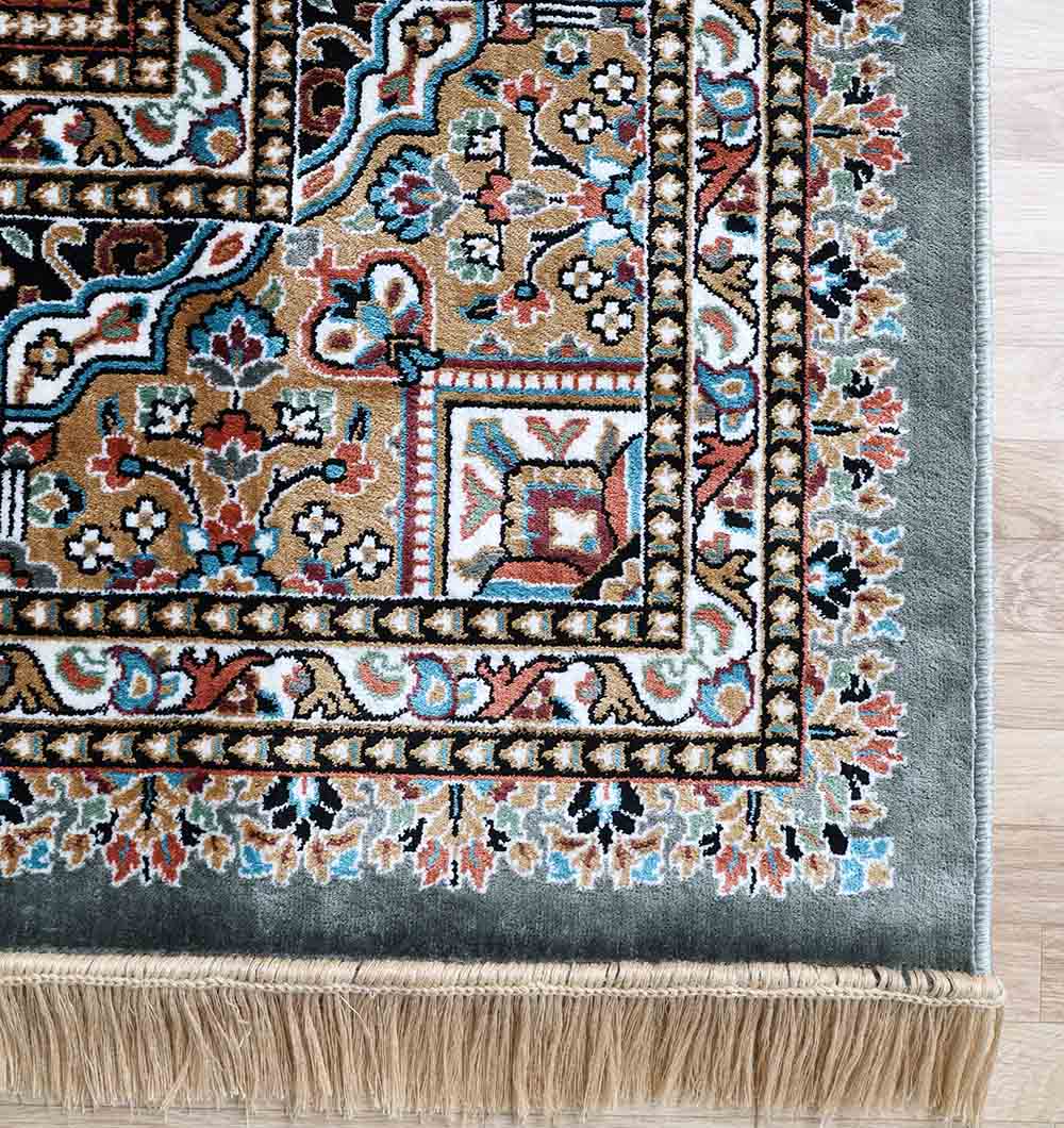 A close-up of the Persian Patchwork Medallion Multicolor Rug – MMB 19 (265X365 cm) by RAMSHA HOME shows its ornate floral patterns, decorative border, and beige fringe on a light wooden floor.