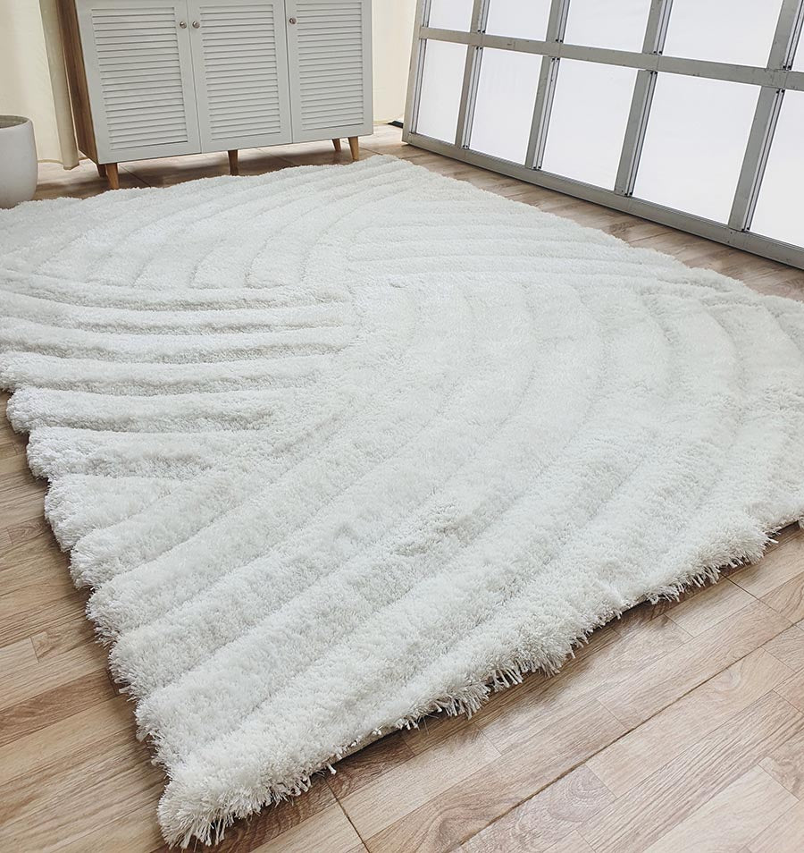 The RAMSHA HOME White Shaggy Area Rug for Large Living Room (MP3D 01) adds wave texture and softness to a bright space with light wood flooring, glass-paneled doors, and modern white furniture.