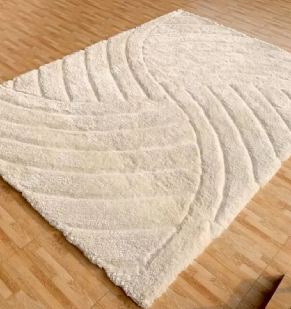 The RAMSHA HOME Textured White Shaggy Area Rug for Large Living Room (MP3D 07) features an ivory color with a carved wave texture and wavy, embossed pattern, adding modern, abstract style to light wood floors.