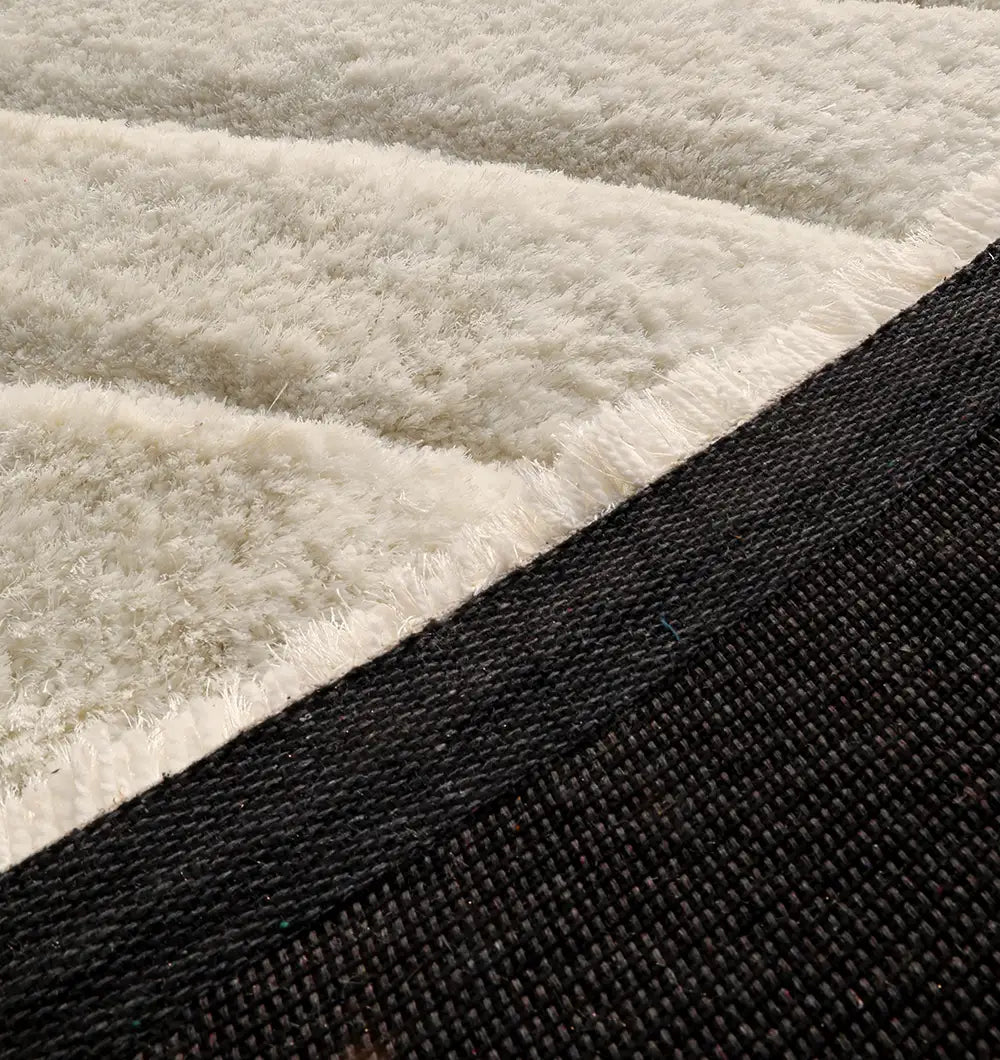 Close-up of the RAMSHA HOME Textured White Shaggy Area Rug for Large Living Room (MP3D 07), showing its cream wave texture and contrasting dark woven border.