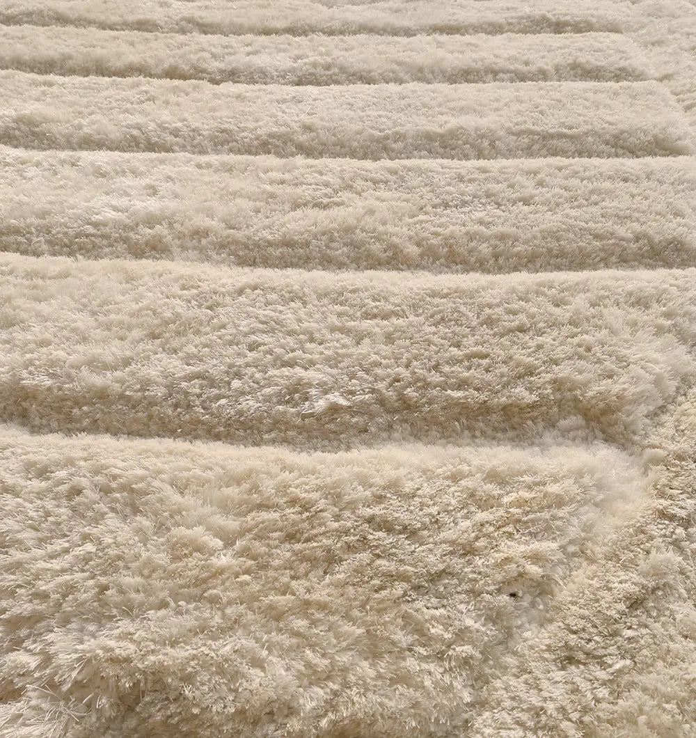 Close-up of the RAMSHA HOME Textured White Shaggy Area Rug for Large Living Room - MP3D 07, highlighting its fluffy, carved wave texture and soft horizontal ridges as sunlight illuminates the cream-white surface.