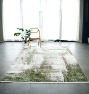 A minimalist room with large windows, sheer white curtains, a single wooden chair, a potted plant, and the RAMSHA HOME Cream Green Machine Made Turkish Rug - MR165 FLORENCE featuring white accents on a gray tile floor.