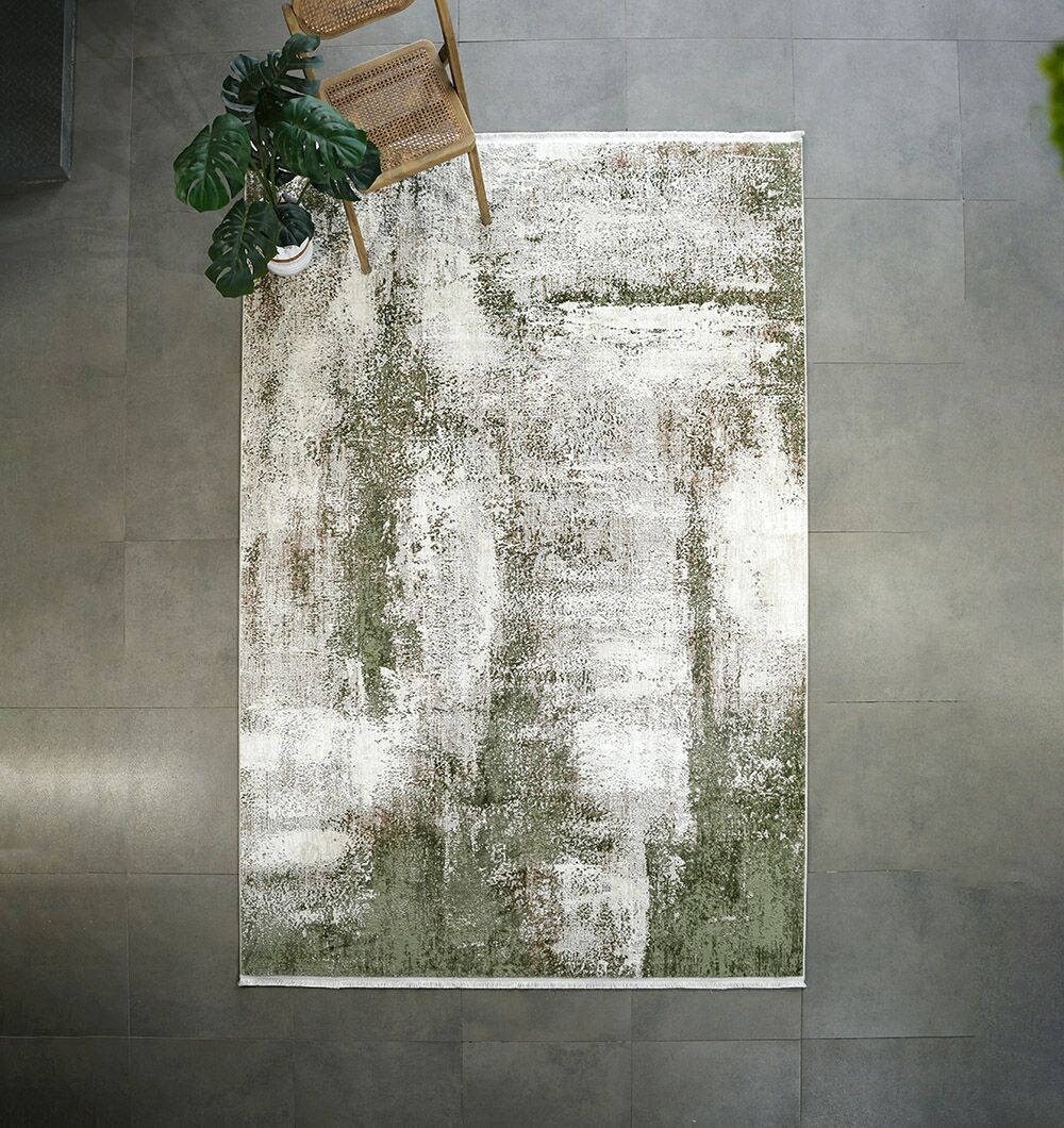 The RAMSHA HOME Cream Green Machine Made Turkish Rug - MR165 FLORENCE with modern abstract patterns lies on a gray tiled floor, complemented by a wooden chair and a leafy potted plant in the top corner.