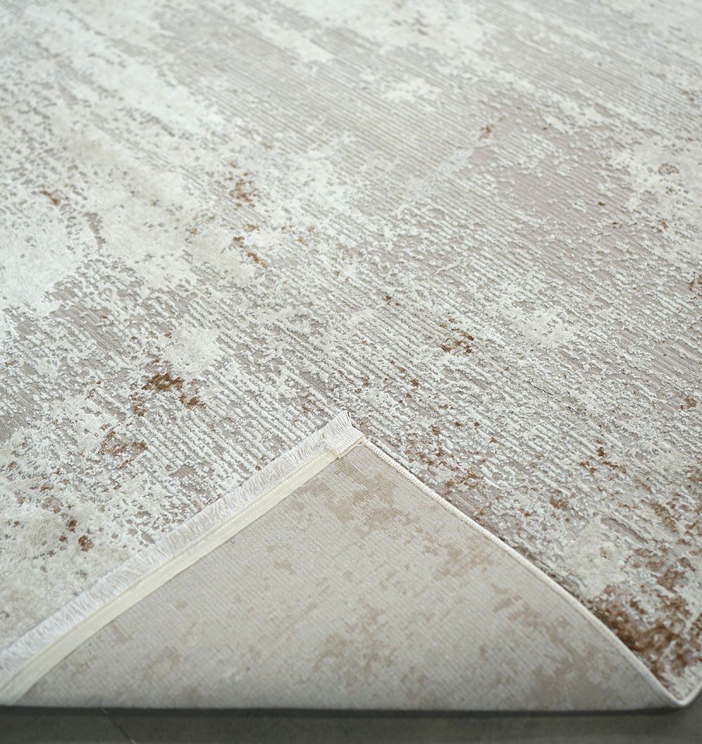A close-up of the Cream Gold Machine Made Turkish Rug - MR172 FLORENCE by RAMSHA HOME, featuring a subtle textured pattern in grey beige tones with one corner folded to display the backing.