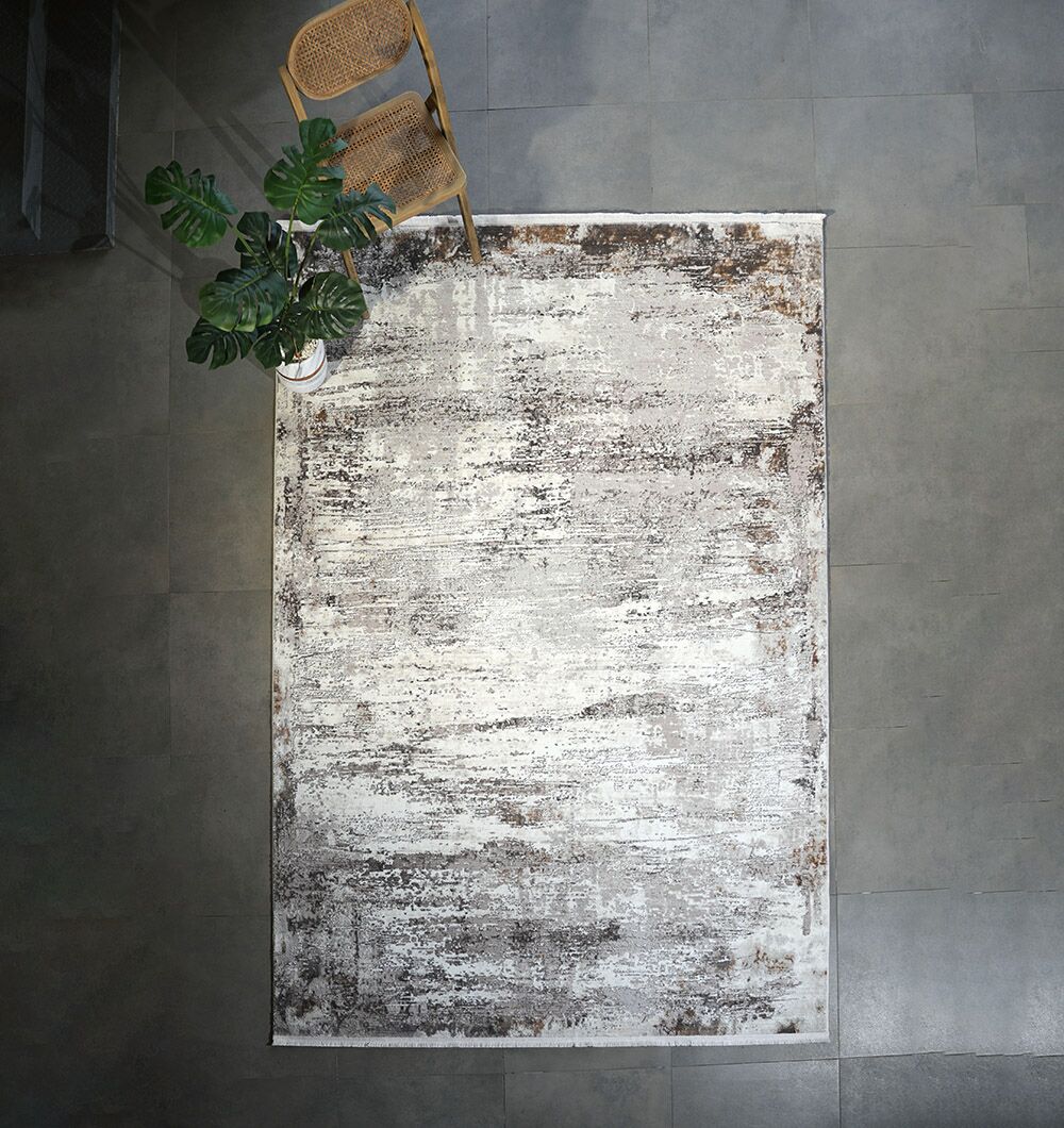 The D.Vizon Gold Machine Made Turkish Area Rug - MR267 FLORENCE by RAMSHA HOME brings a stylish distressed beige and brown pattern over a gray tile floor, topped with a wooden chair and potted plant for added texture.