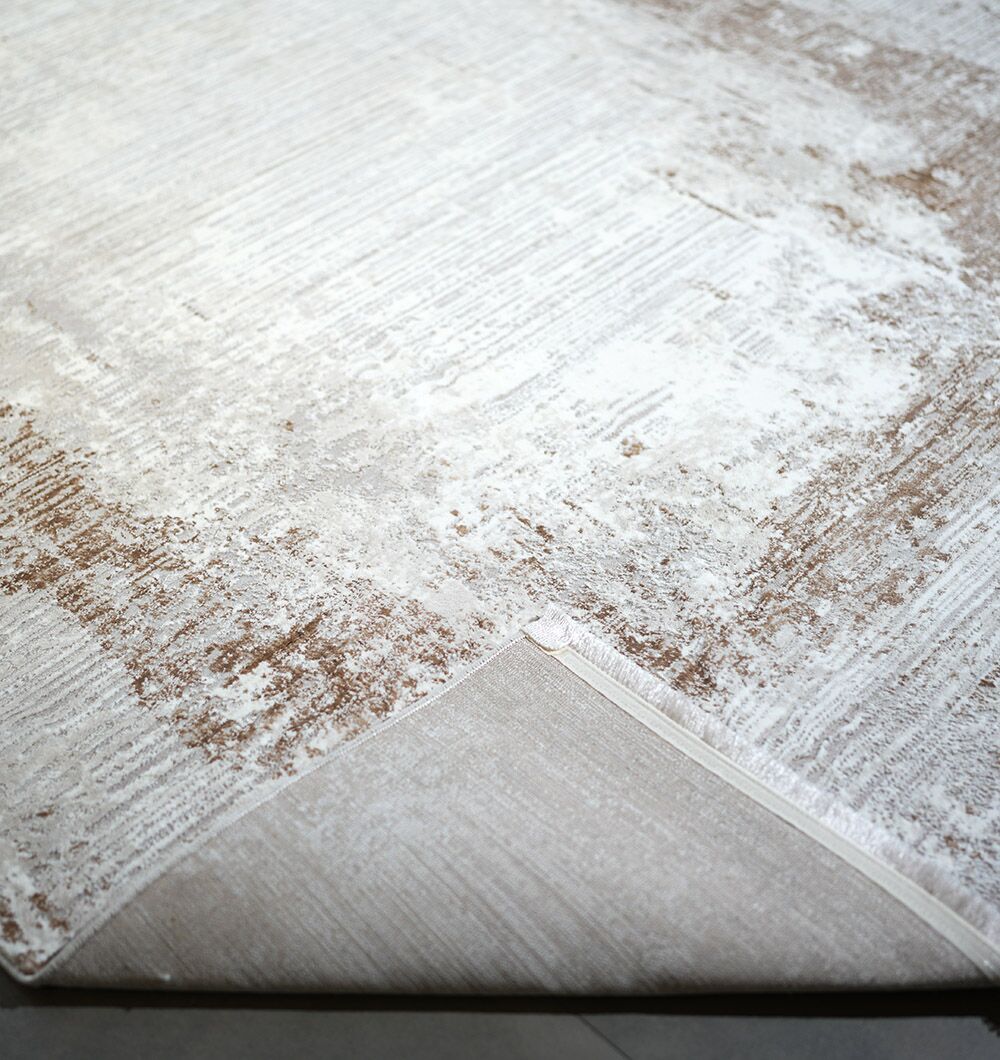 A close-up of the RAMSHA HOME Machine Made Cream Gold Color Turkish Rug - MR359 FLORENCE shows its subtle, vintage-inspired pattern and elegant stitched edge, with the corner lifted to reveal the plain underside.