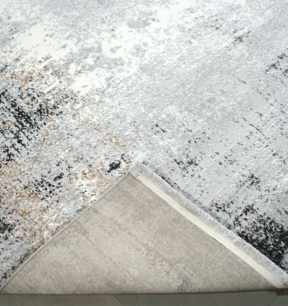 A close-up of the RAMSHA HOME Machine Made Turkish Area Rug - MR529 FLORENCE shows its modern grey, beige, and black abstract design. One corner is flipped to display the underside and stitching, highlighting this rug's unique texture.