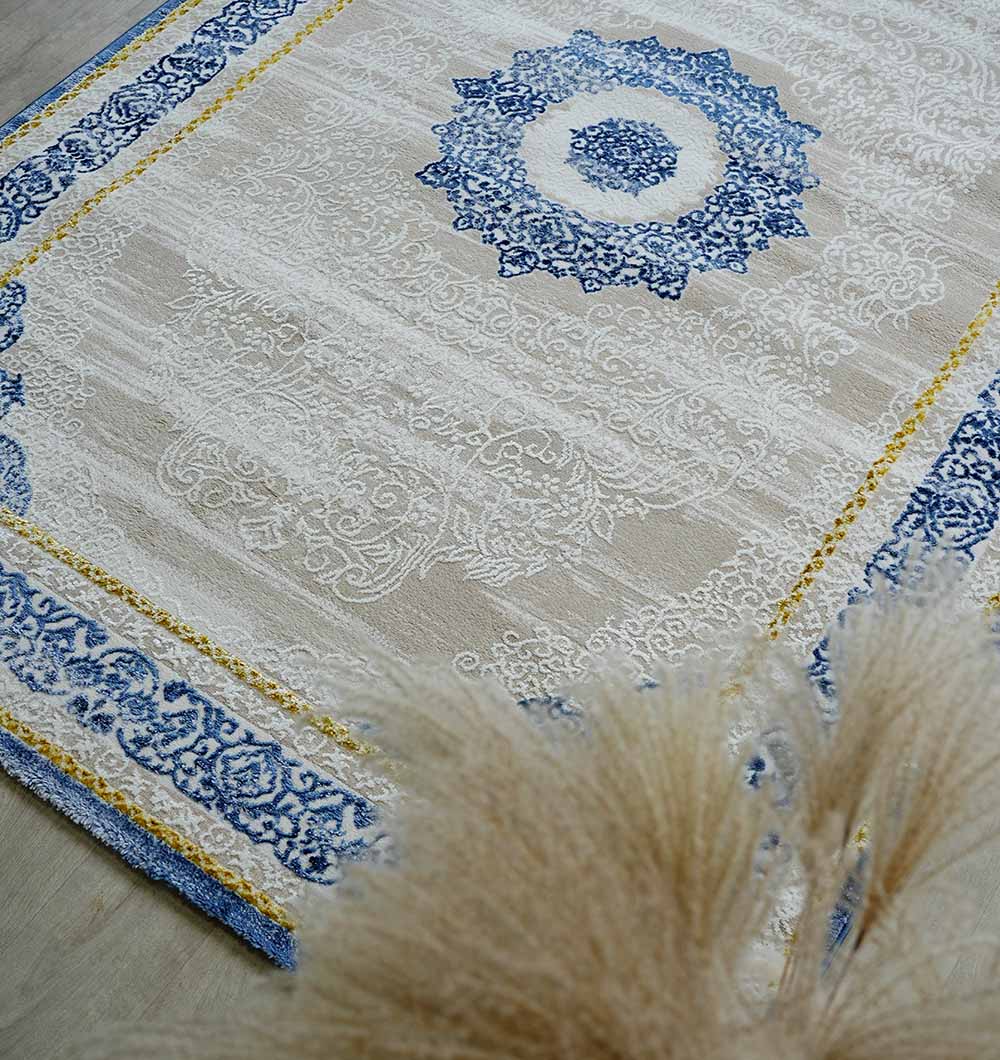 The RAMSHA HOME Machine Made Turkish Area Rug - N370A MADRID features a cream base, blue and white medallion, blue and gold border, ornate patterns, and beige pampas grass visible in the lower right corner.
