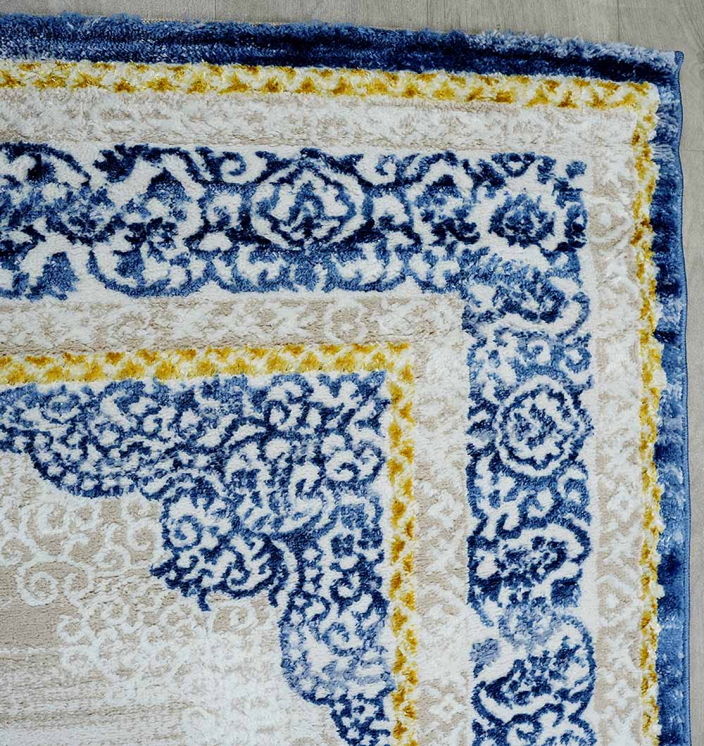 Close-up of the RAMSHA HOME Machine Made Turkish Area Rug - N370A MADRID, showing intricate blue patterns, yellow accents, and a beige background with a blue border, resting on a light wood floor.