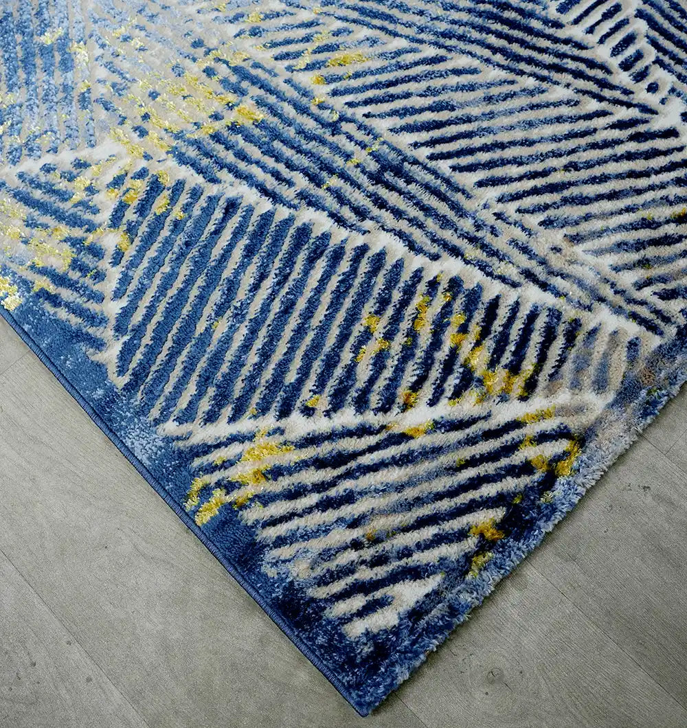 A close-up of the RAMSHA HOME Abstract Geometric Machine Made Turkish Area Rug - N405A MADRID, featuring diagonal blue, white, and yellow stripes with geometric patterns, displayed on a light wood floor.