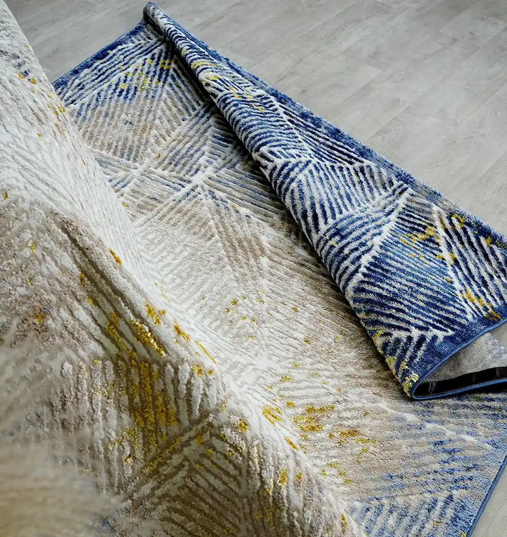 Close-up of the RAMSHA HOME Abstract Geometric Machine Made Turkish Area Rug (N405A MADRID), featuring blue, white, and gold patterns.
