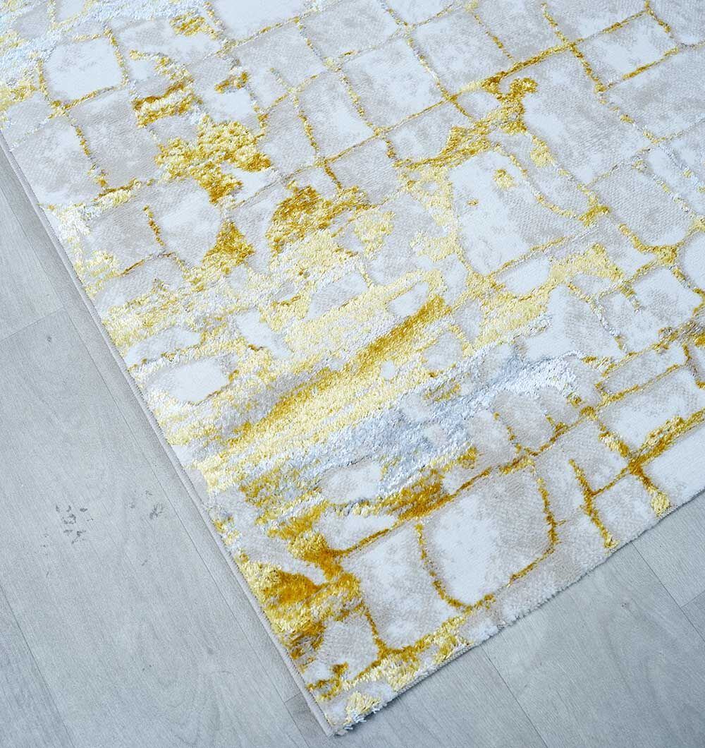 The RAMSHA HOME Abstract Machine Made Ivory & Yellow Turkish Area Rug (NK81A MADRID) features an abstract yellow and gold Persian-inspired pattern on a white and gray base, displayed atop a light gray wooden floor.