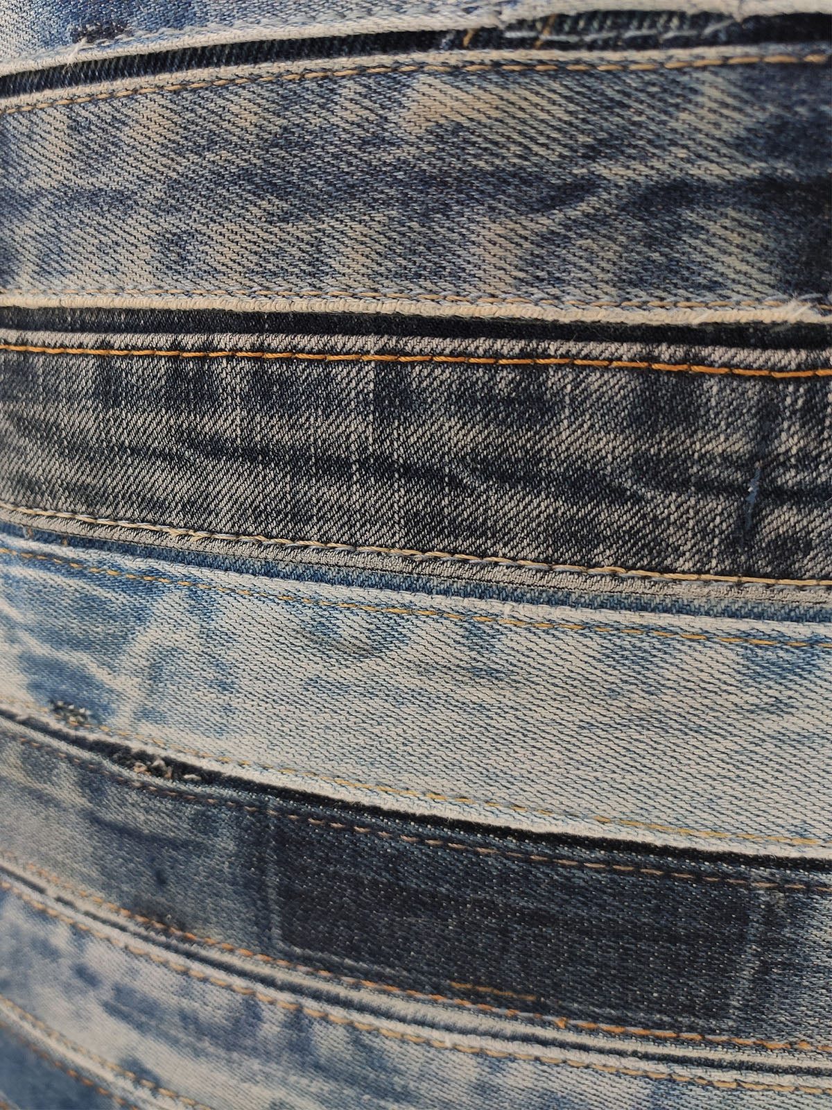 Detailed macro shot of blue denim cylindrical pouf highlighting stitching pattern, woven surface, and material craftsmanship.