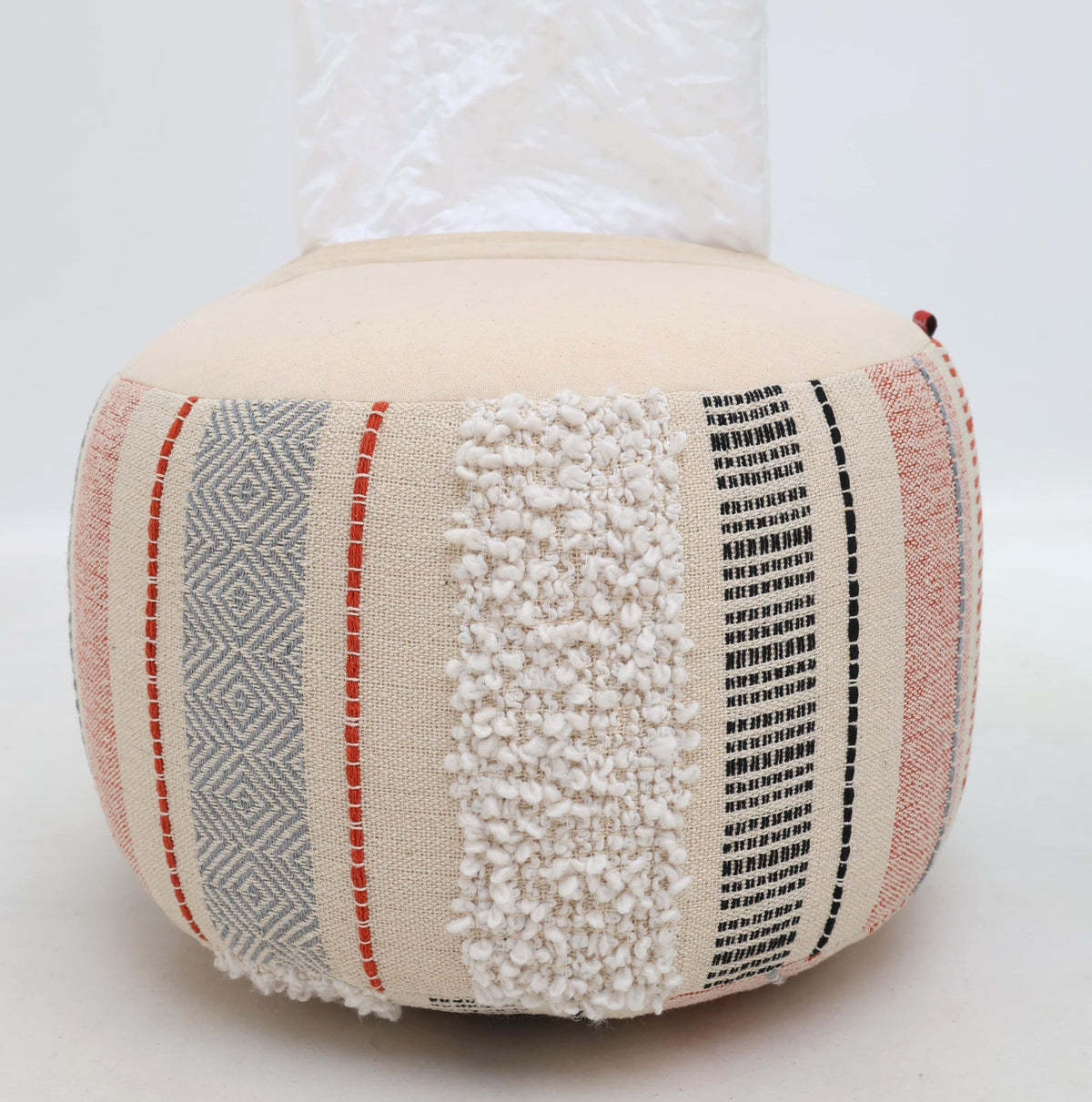 The RAMSHA HOME Boho Modern Round Pouf With Insert PF 105, crafted from cotton with vertical stripes in red, gray, and black and showcasing a mix of woven and textured patterns, rests on a light-colored floor against a white backdrop—an ideal choice for extra seating or as a stylish accent piece.