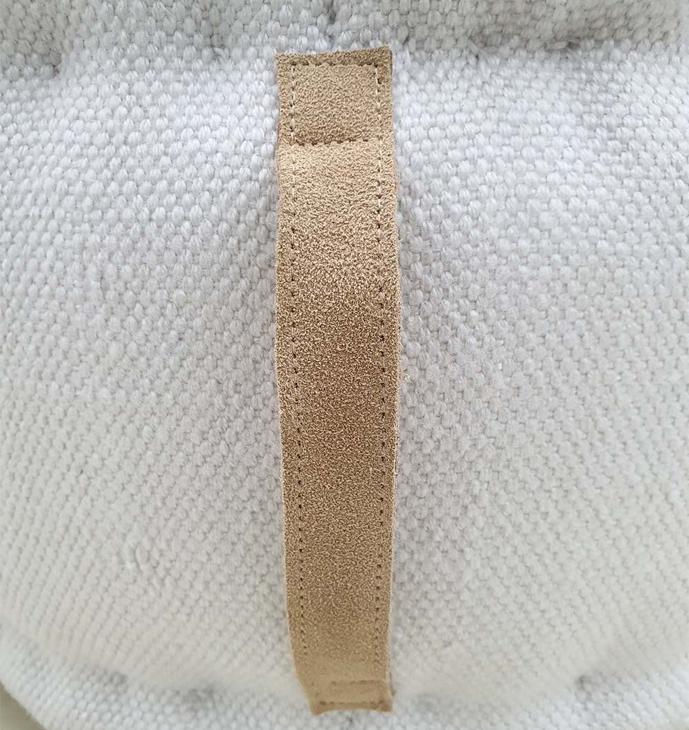 Modern woven pouf with side handle, crafted from 100% polyester for elegant home seating