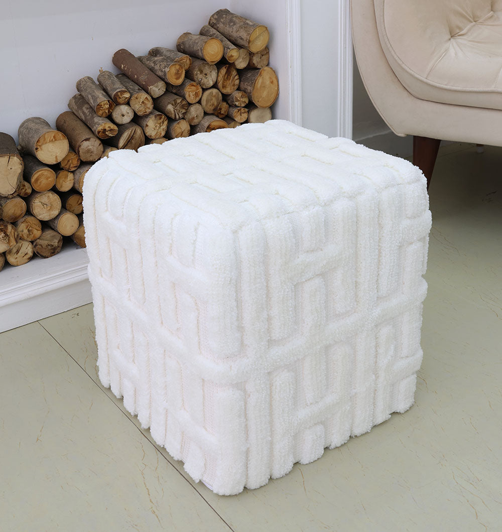 The RAMSHA HOME Luxury Handmade Pouf with Thermocol Bean Bag Insert PF-151, featuring a white geometric texture, sits on a light floor near a beige armchair and stacked firewood, adding premium décor to the space.