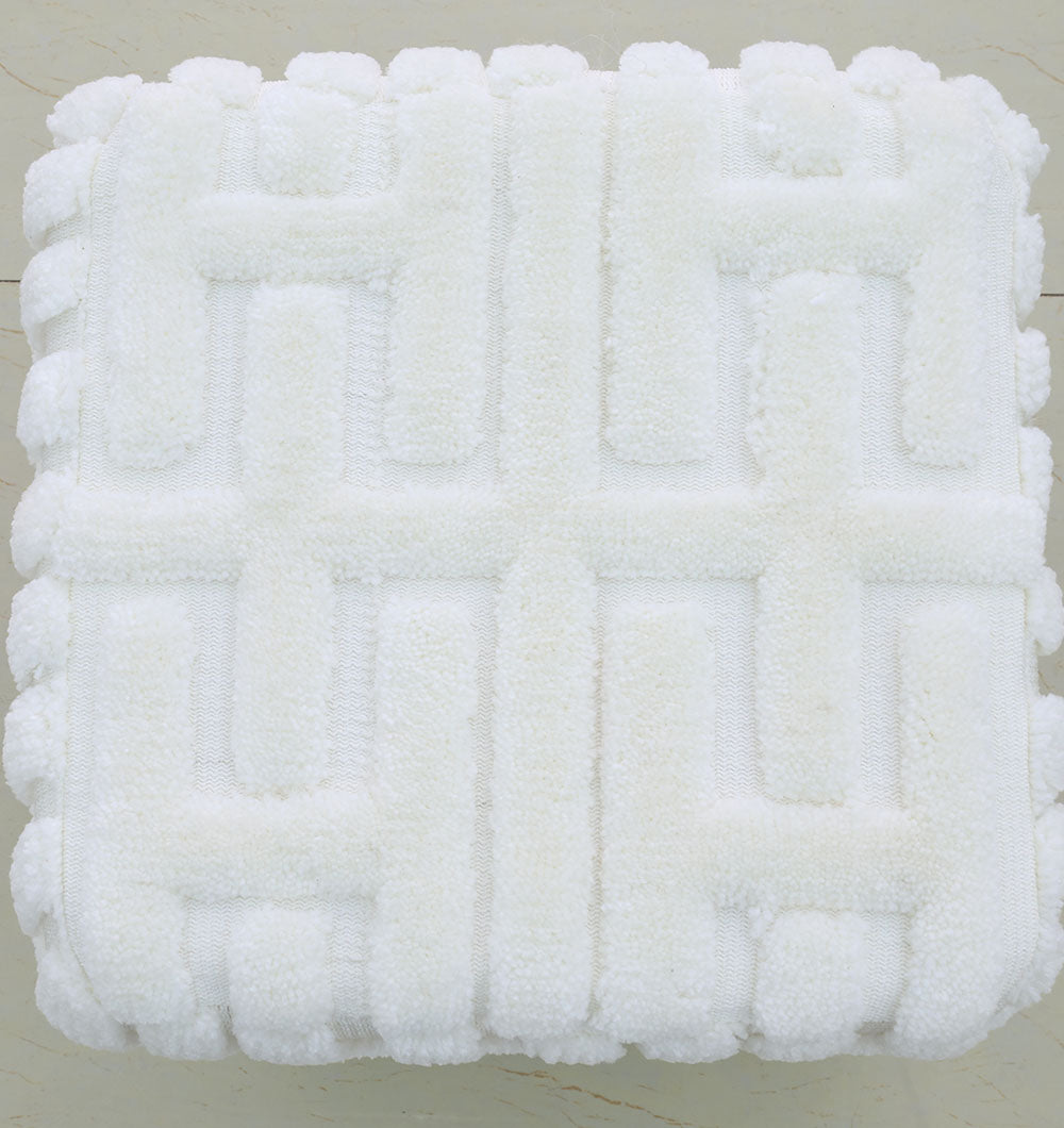 A white, square Luxury Handmade Pouf (PF-151) by RAMSHA HOME, featuring a textured geometric pattern and thermocol bean bag insert, adds a premium décor touch on a light-colored tiled floor.