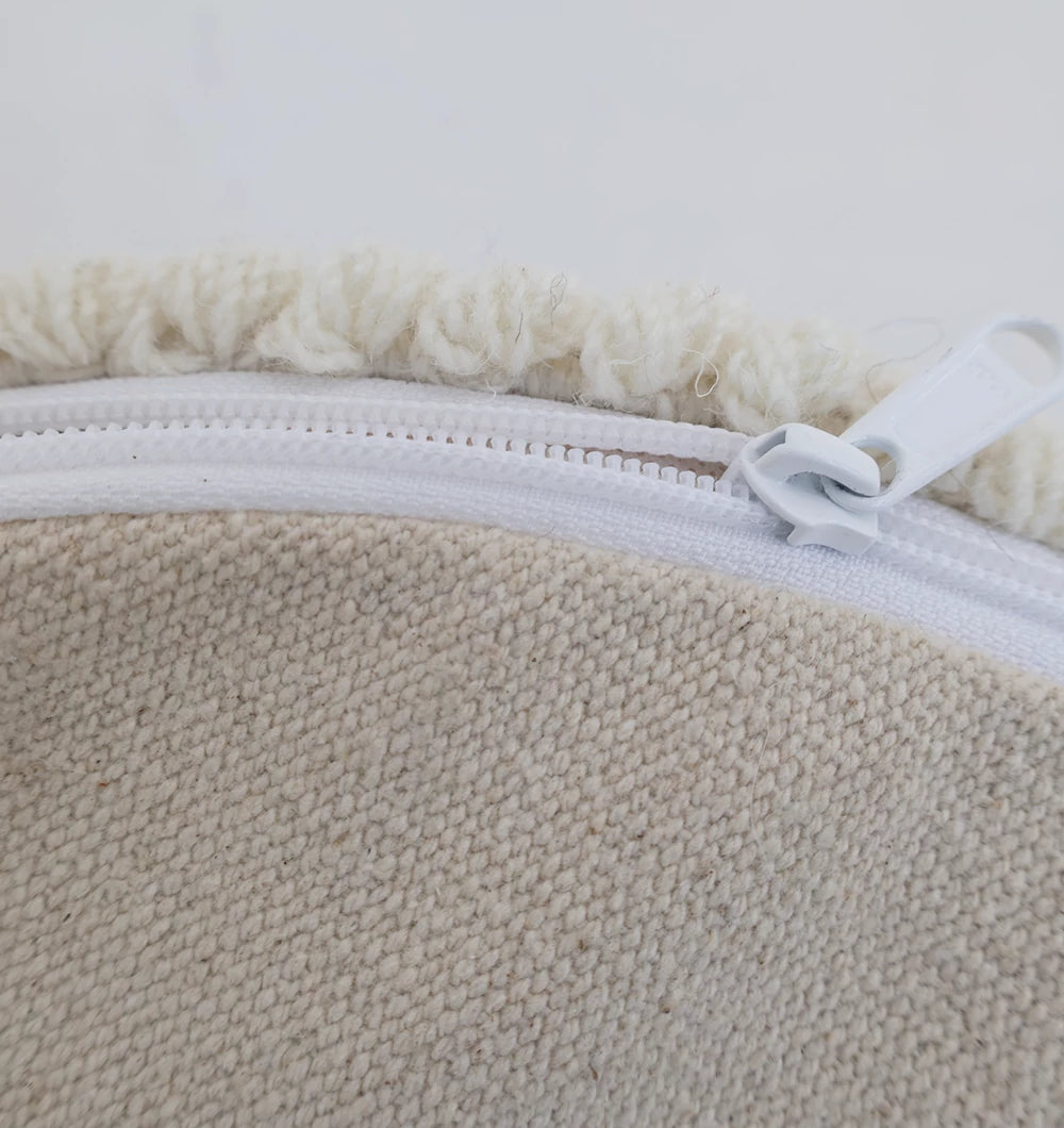 Close-up of a white zipper partially opened on the Handwoven White Macrame Pouf with Bean Bag Insert PF 161 by RAMSHA HOME, revealing off-white, fluffy material—ideal for finishing this textured floor cushion.