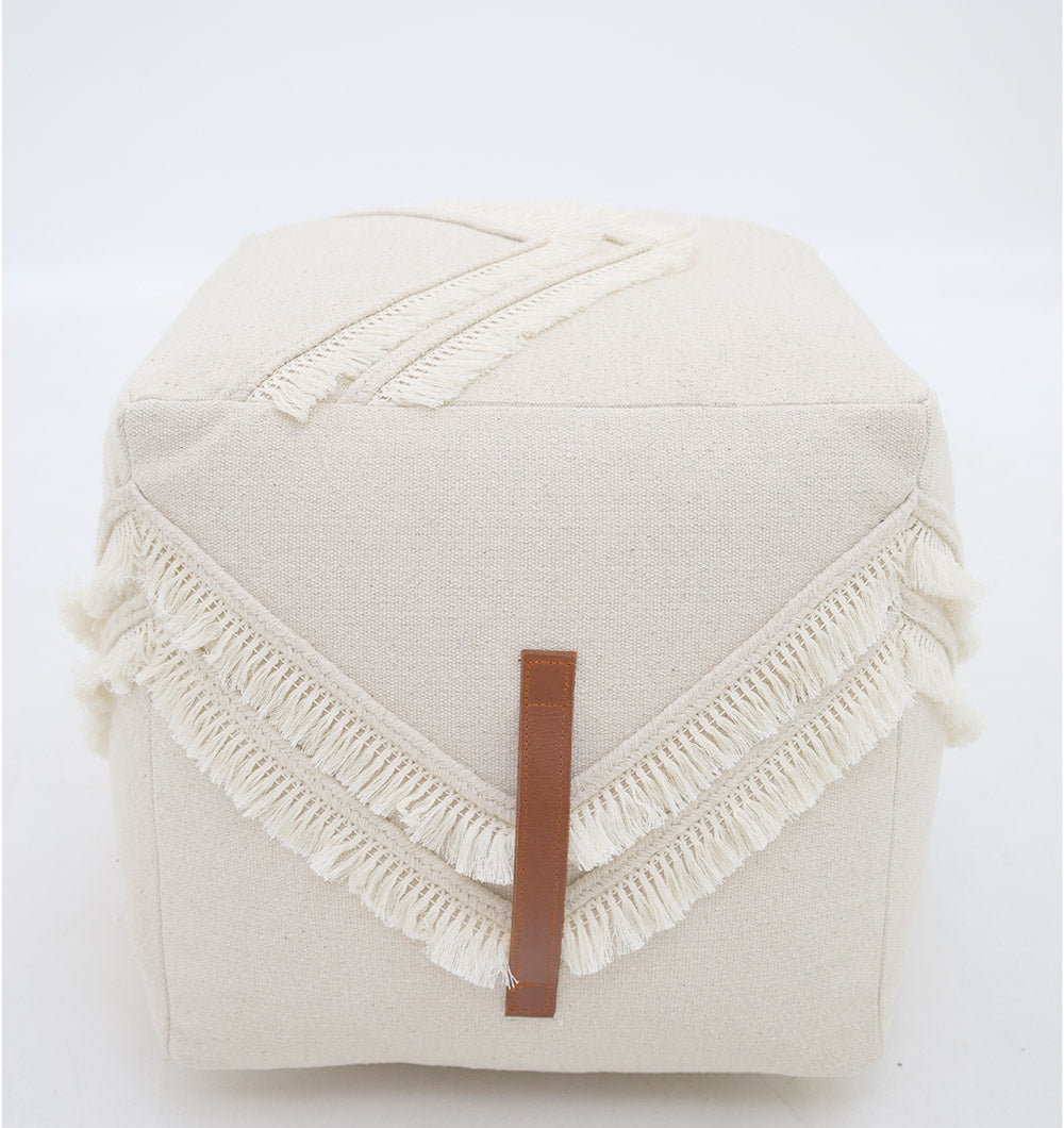 The RAMSHA HOME Ivory Handmade Cotton Pouf with insert PF 166 features a square cotton design, V-shaped fringe, and a brown leather accent, adding chic style as a decorative accent against a plain white background.