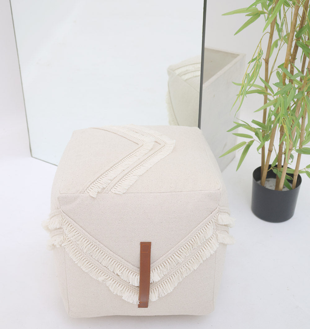 An Ivory Handmade Cotton Pouf with insert PF 166 by RAMSHA HOME sits near a mirror and a potted bamboo plant on a white floor. The mirror reflects this decorative accent and part of the plant.