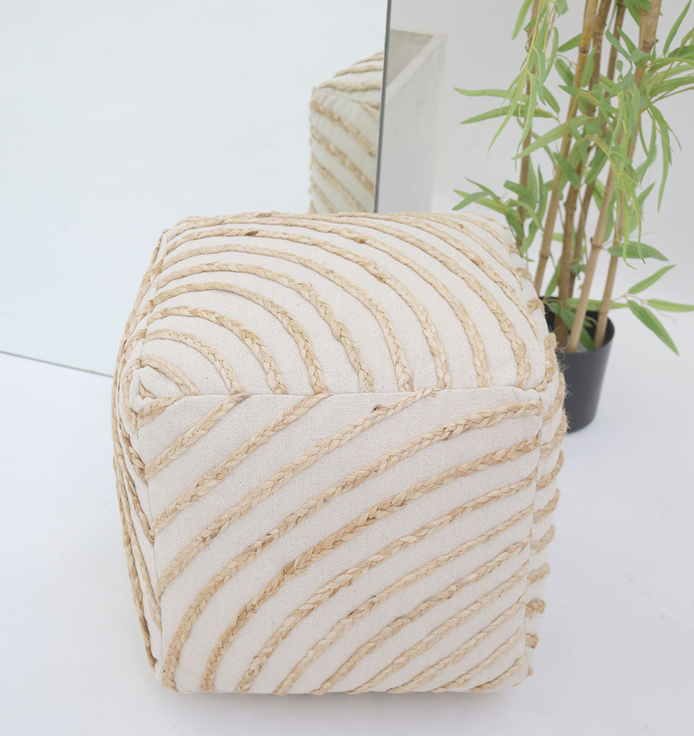 The Aurora Cotton Floor Pouf with insert PF 173 by RAMSHA HOME, a cream cube with diagonal textured stripes, sits on a white floor beside a green plant and large mirror, bringing cozy modern style as both reflect in the mirror.