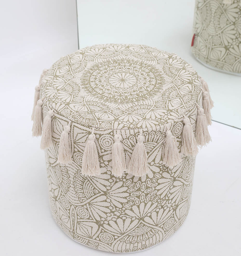 The Stylish cotton printed pouf with decorative tassels PF 174 by RAMSHA HOME, featuring intricate floral embroidery and beige boho design, is reflected in a mirror as it sits on a white floor.