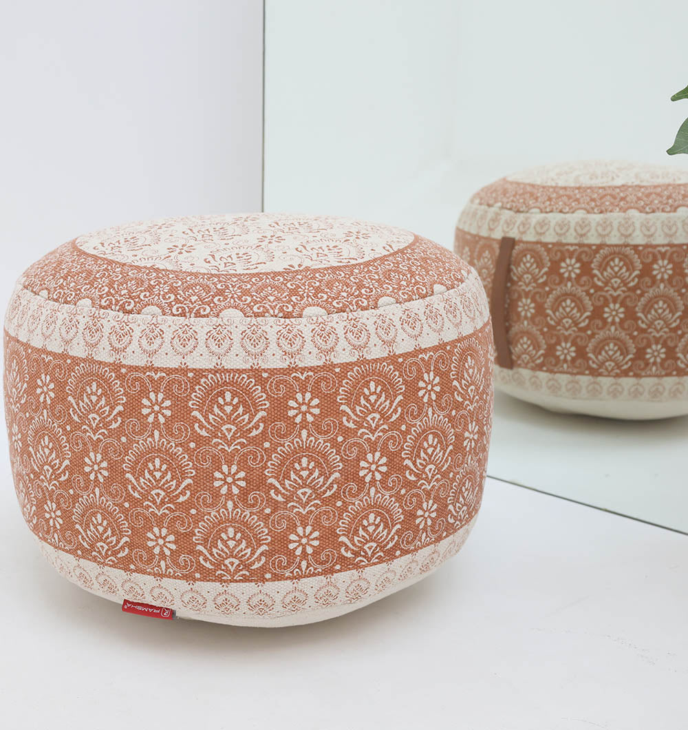 The RAMSHA HOME Round Bohemian Printed Pouf with Comfortable Insert PF 180 rests on a white floor near a mirror, showcasing its detailed design and adding stylish seating beside a leafy green plant.