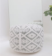 The RAMSHA HOME Round Bohemian Printed Pouf with Comfortable Insert PF 183 in light gray and white geometric diamond pattern sits stylishly in front of a mirror, complemented by a green leafy plant visible on the right.