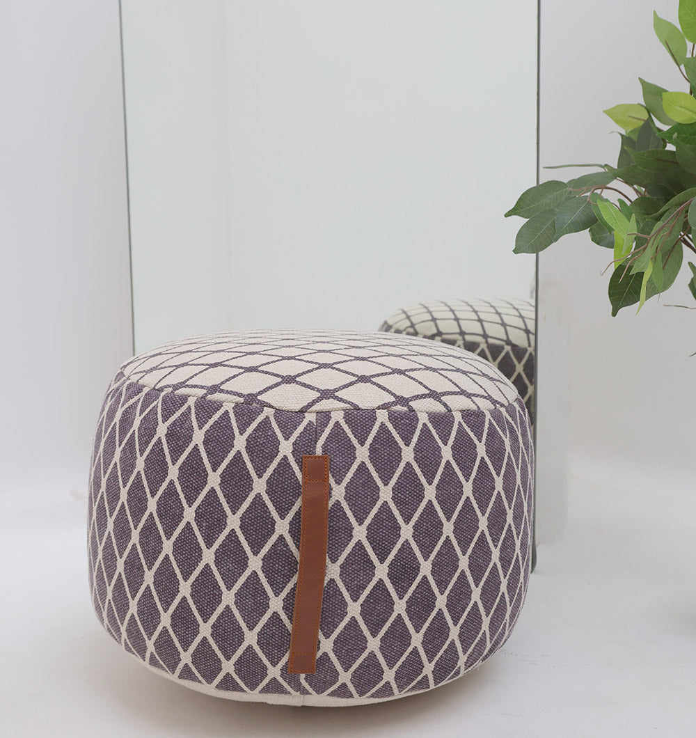 The RAMSHA HOME Modern Diamond Pattern Round Pouf with Comfortable Insert PF 184, in purple and white with a brown handle, sits before a mirror. A green leafy plant on the right adds an inviting touch to your home décor.