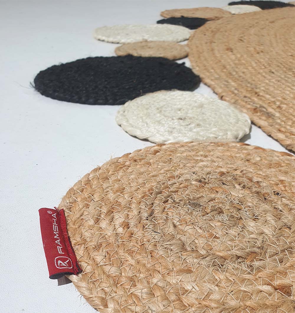 A close-up of the Jute Natural Rug Round BR-029 by RAMSHA HOME shows circular patterns in beige, white, and black with a red RAMSHA HOME tag attached to the beige edge.