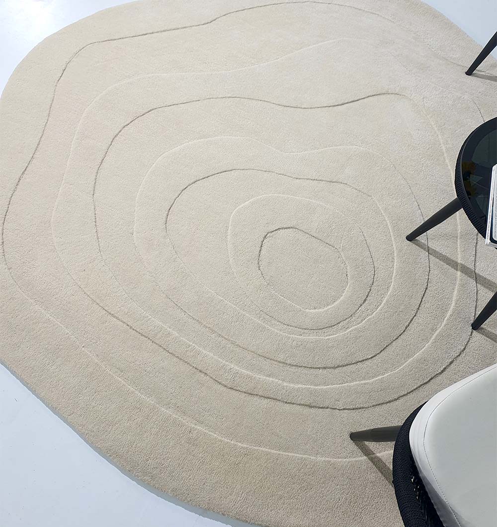 The Luxurious Multi Color Round Handmade Rug - HTW 63 (200cm) by RAMSHA HOME adds elegance with its concentric line design, paired stylishly with a black round table and a white chair in the corner.