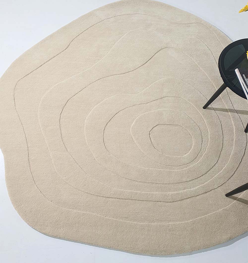 The Luxurious Multi Color Round Handmade Rug - HTW 63 (200cm) by RAMSHA HOME, with its hand-tufted concentric wavy lines, rests on a light floor beside a round black table decorated with books and a yellow flower.