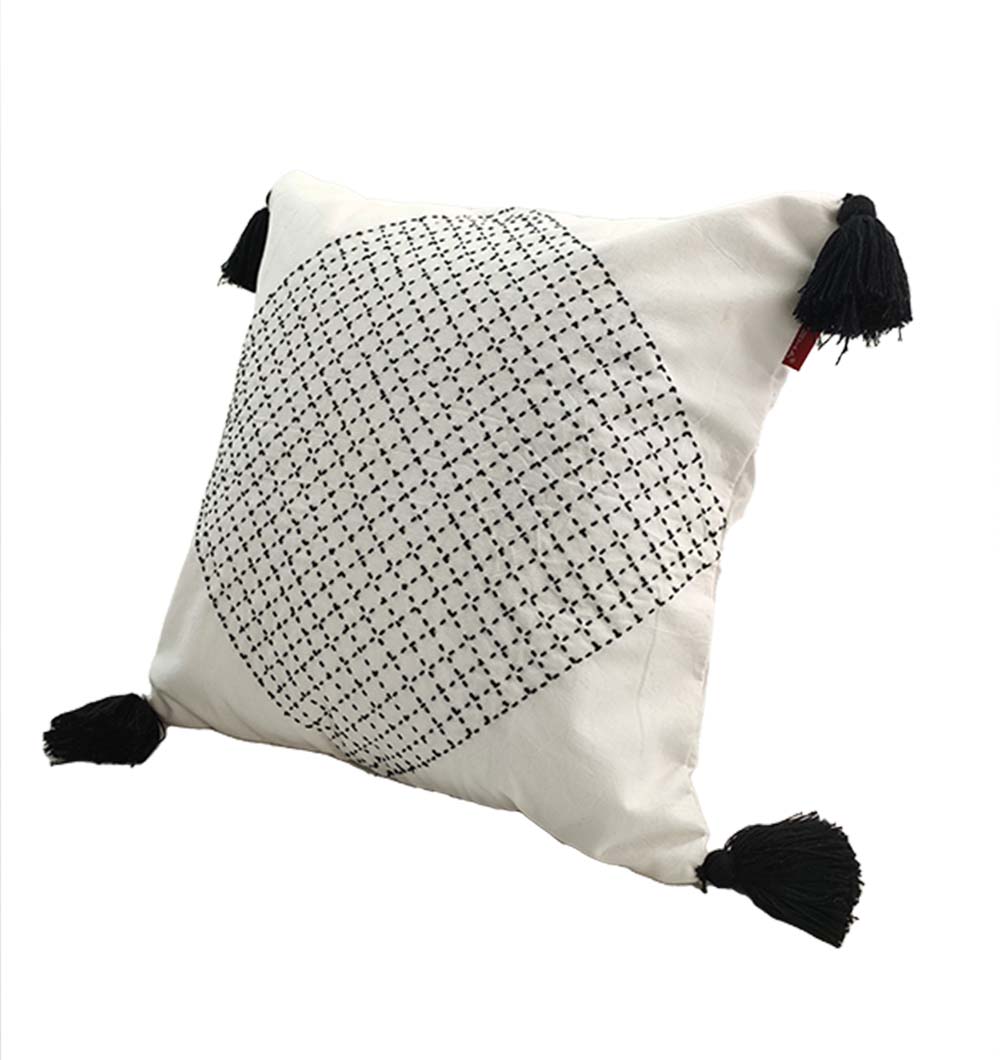 The RAMSHA HOME Embroidery White And Black Cotton Cushion With Tassel CS-194 features a central black geometric embroidery, black tassels on each corner, and a crisp white cotton cover—ideal for modern home décor.