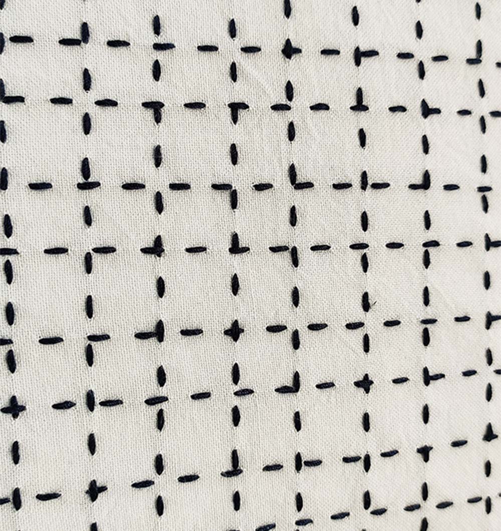 Close-up of the RAMSHA HOME Embroidery White And Black Cotton Cushion With Tassel CS-192, featuring a modern black grid pattern on white fabric—an elegant, understated addition to your decor.